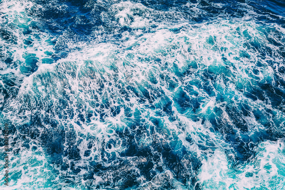 Top aerial view of blue ocean waves texture from above white foam sea background.