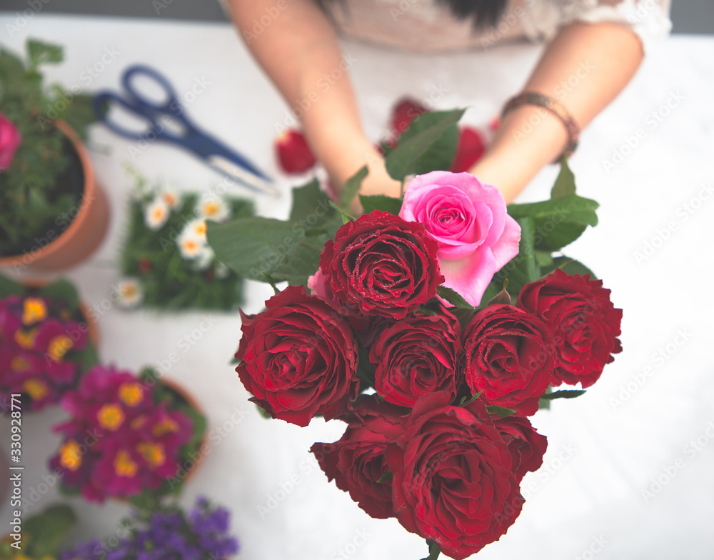 Woman Preparing to trim red and pink roses and beautiful flower arrangements in the home, flower arr