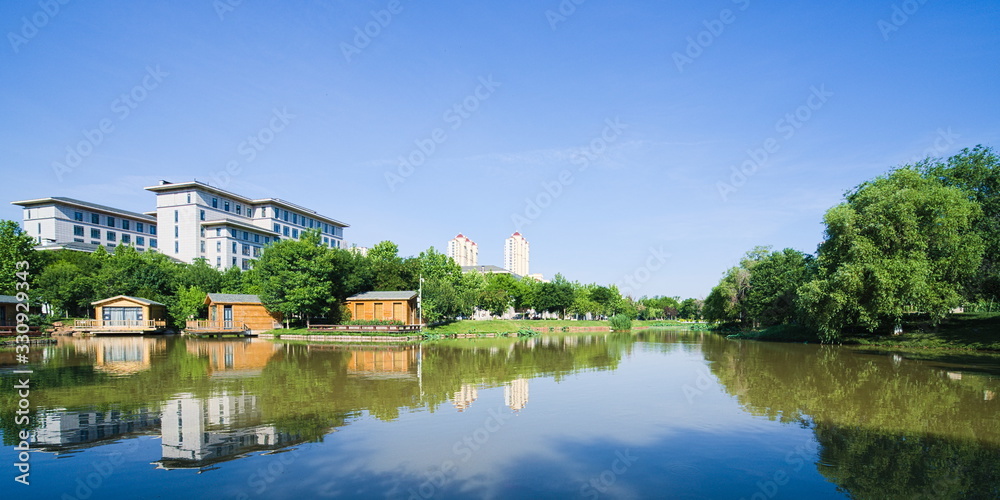 Lake scenery near the city buildings under sunny blue sky