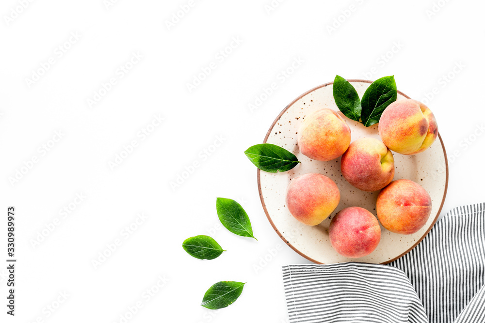 Summer lunch. Red peaches on white background with tablecloth and leaves top-down copy space