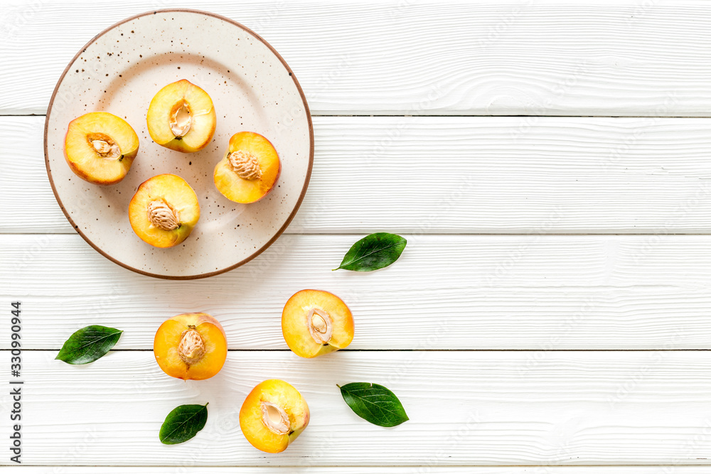 Healthy food. Ripe sliced peaches on plate on white wooden table top-down copy space