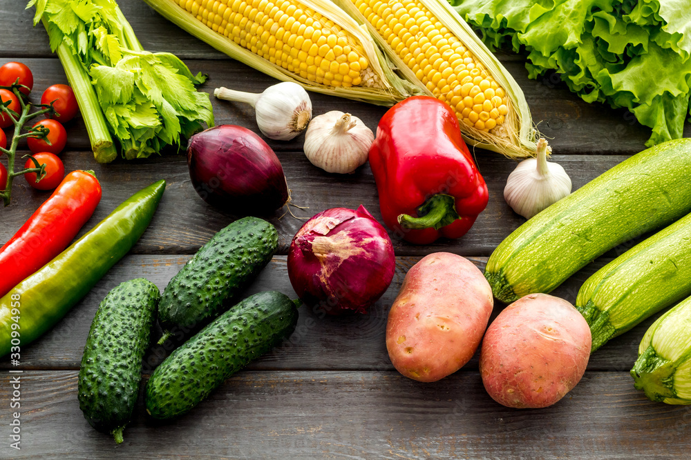 Fresh vegetables still life. Potato, cucumber, beet carrot, greenery on dark wooden background