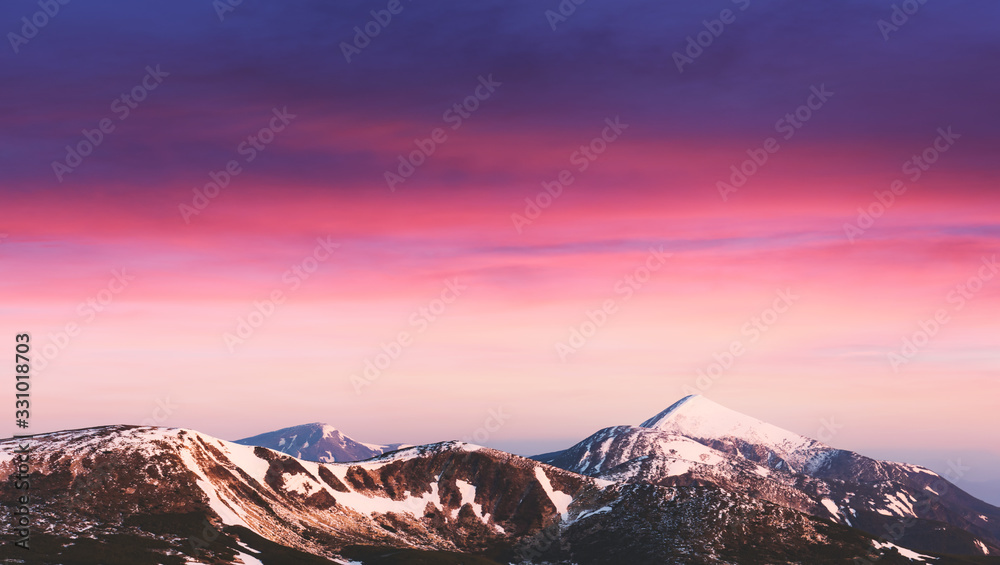 背景为雪山山峰上闪耀的紫色日出光。风景摄影