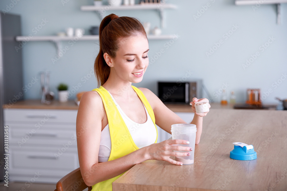 Sporty young woman making protein shake at home