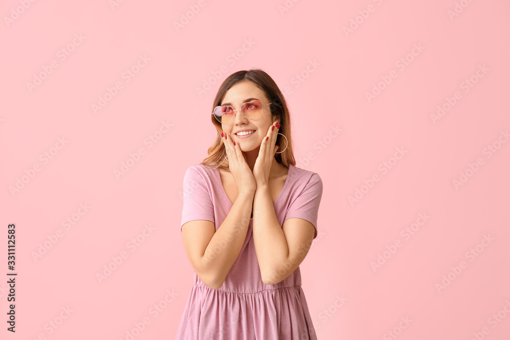 Young woman with stylish sunglasses on color background