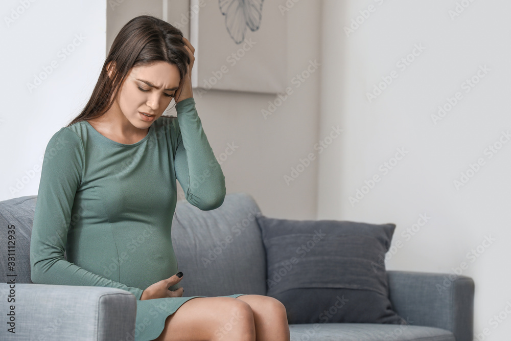 Depressed young pregnant woman at home