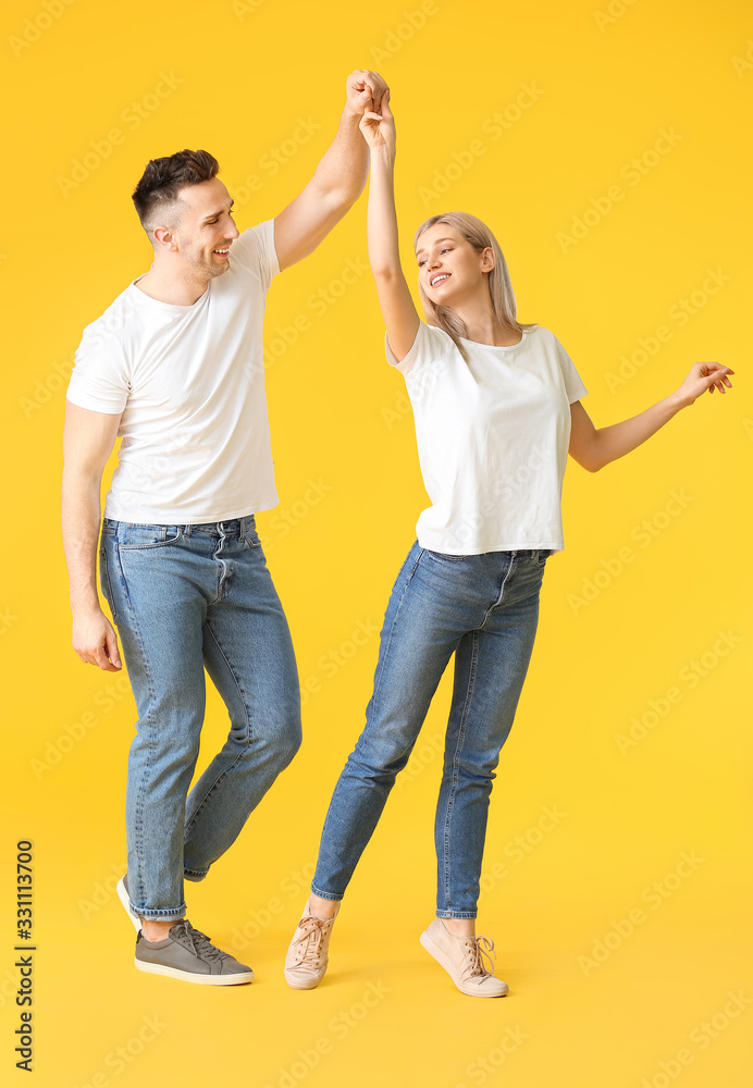 Happy dancing young couple on color background