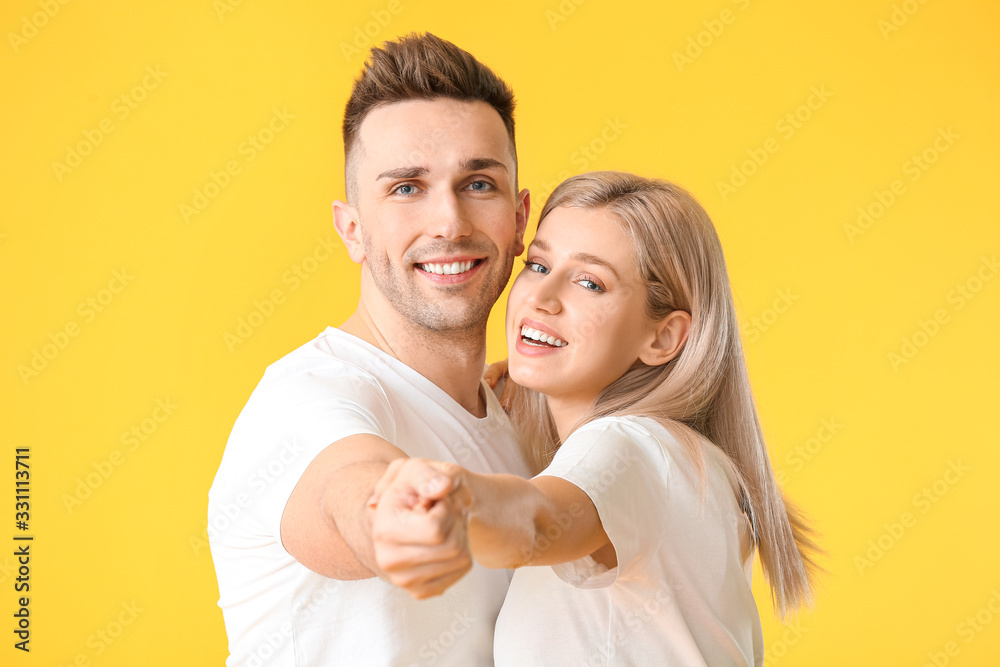 Happy dancing young couple on color background