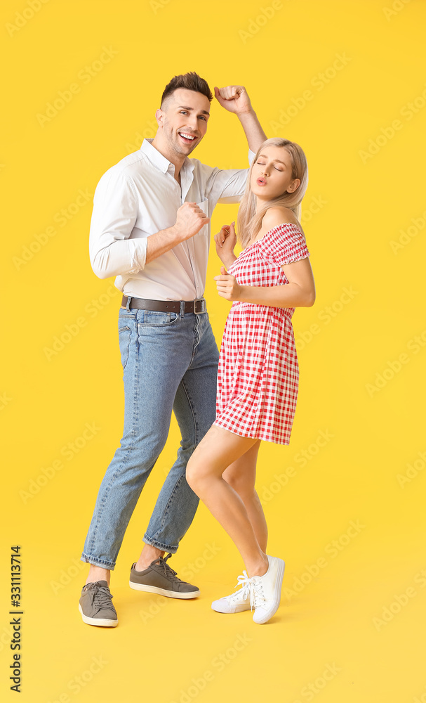 Happy dancing young couple on color background