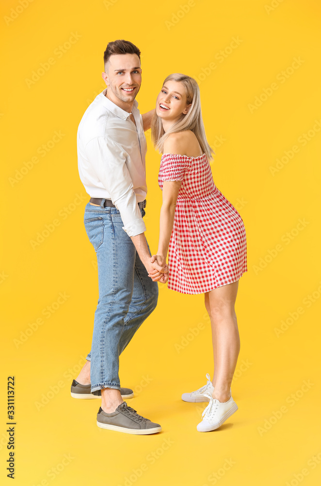 Happy dancing young couple on color background