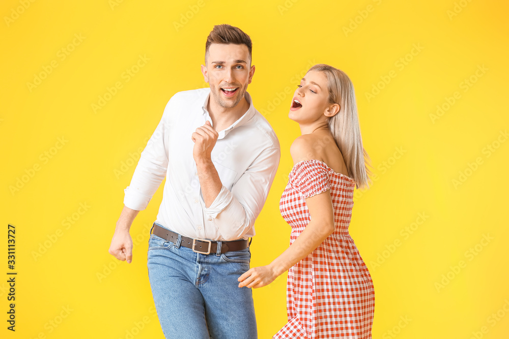 Happy dancing young couple on color background