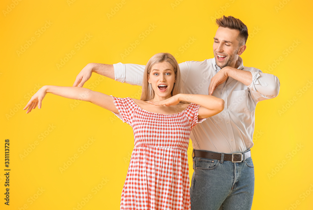 Happy dancing young couple on color background