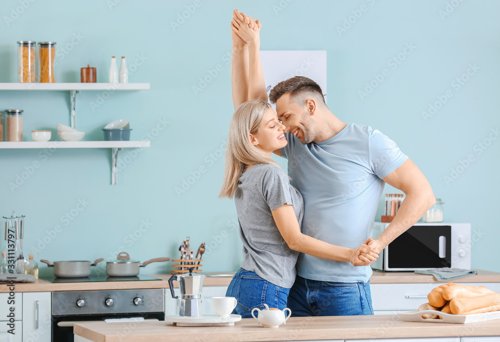 Happy dancing young couple in kitchen