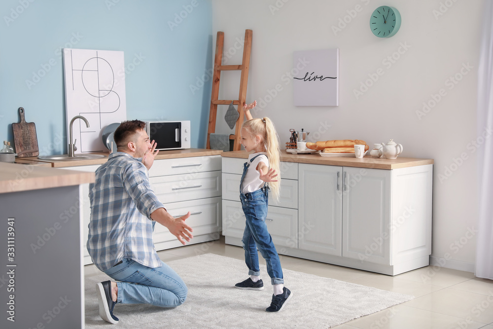 Man and his little daughter dancing in kitchen