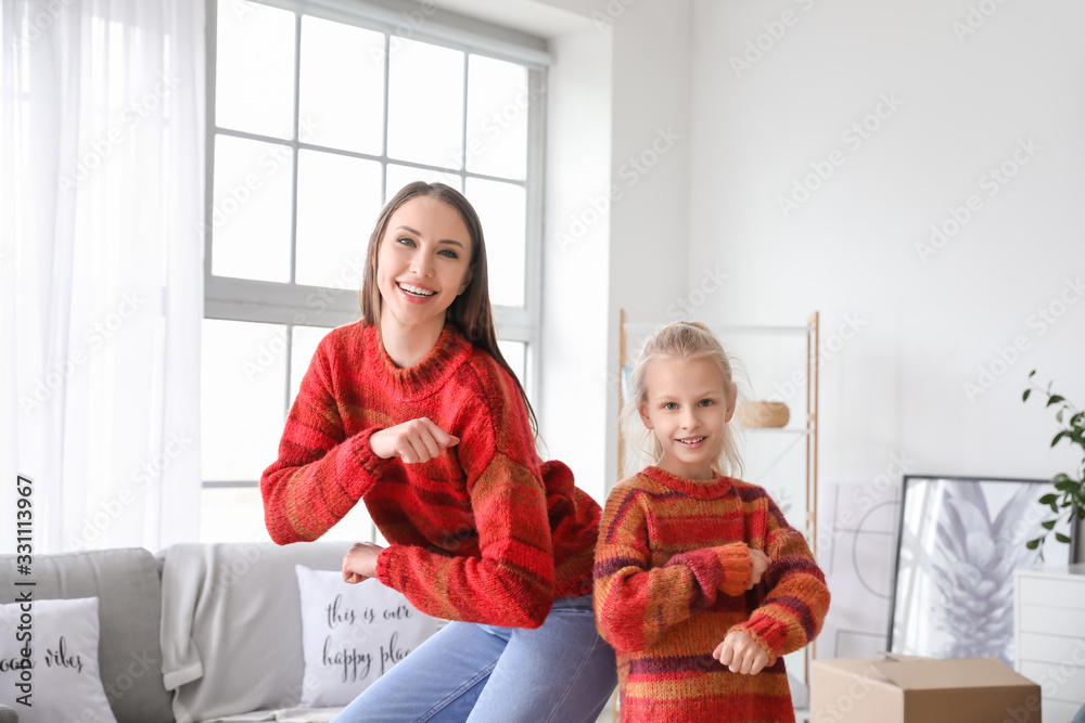 Happy mother and her little daughter dancing at home