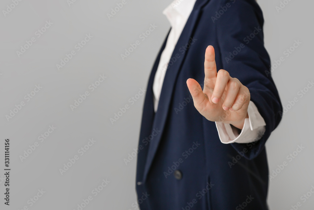 Businesswoman using virtual screen on grey background, closeup