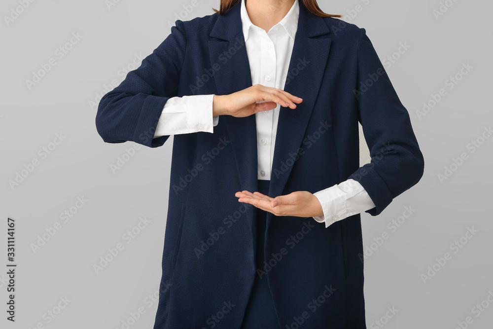 Businesswoman holding something on grey background, closeup