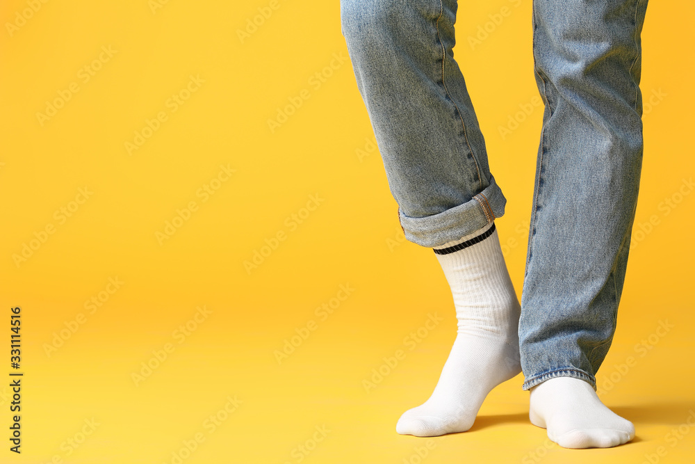 Male legs in socks and jeans on color background