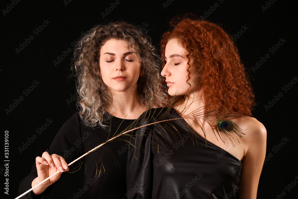 Beautiful young women with peacock feather on dark background