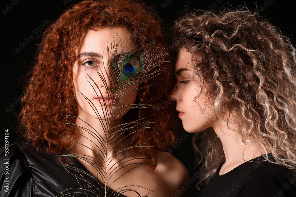 Beautiful young women with peacock feather on dark background