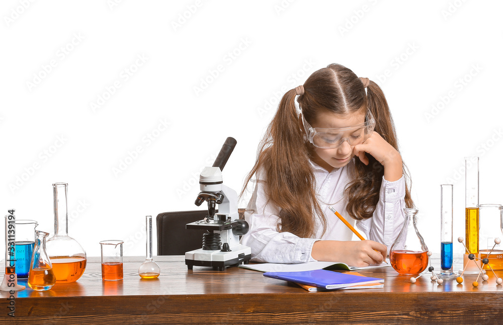 Cute little girl studying chemistry at table against white background