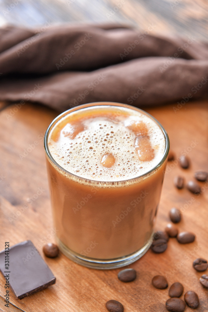 Glass of tasty iced coffee on table