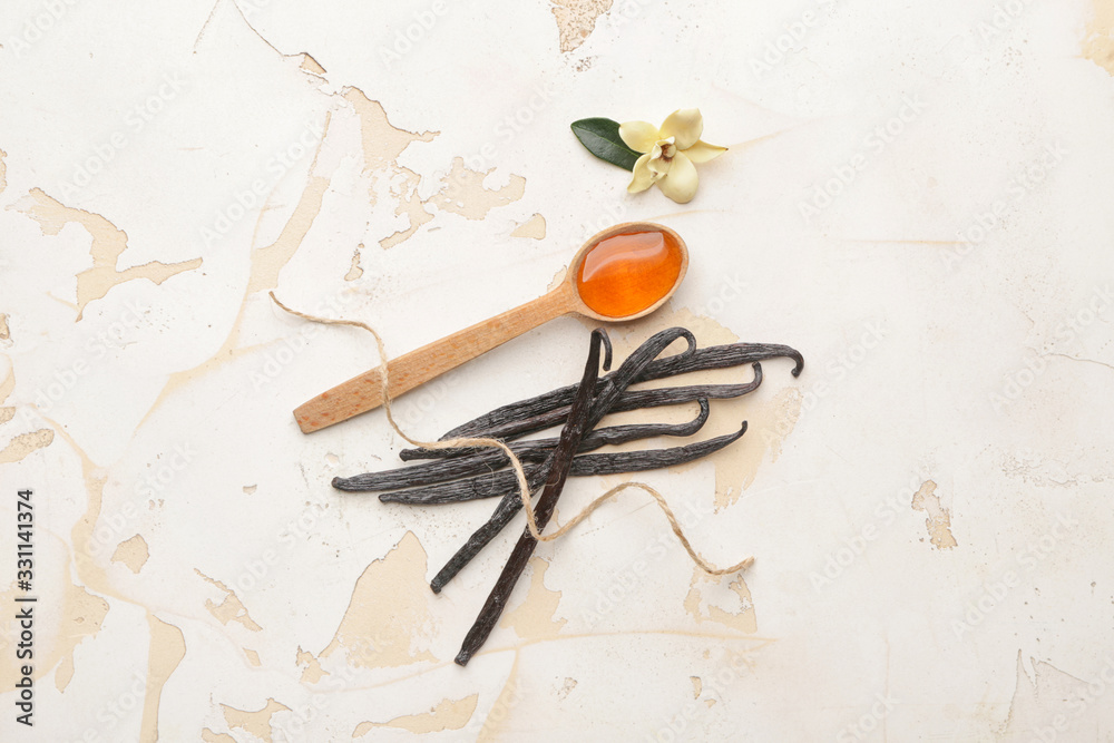 Spoon with aromatic vanilla extract on table