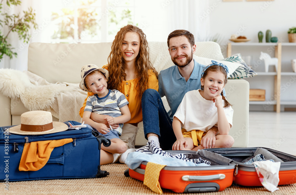 Cheerful family with suitcases on floor looking at camera.