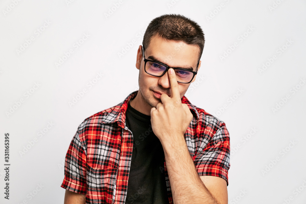 Good looking man in red and white shirt looking over stylish eyeglasses into the camera isolated on 