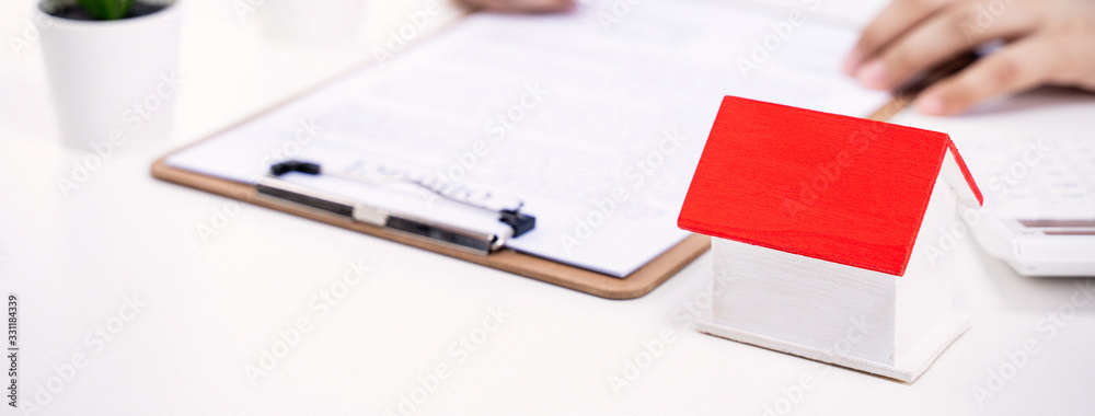 Business concept - Young Asian man in blue shirt calculates, signs agreement contract to buy a house