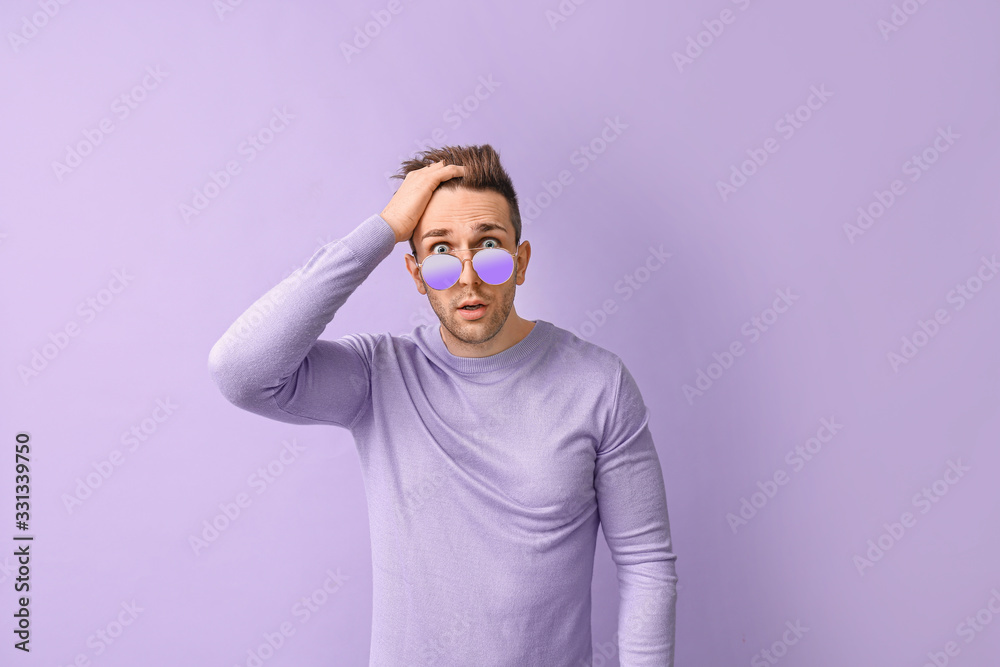 Surprised man with stylish sunglasses on color background