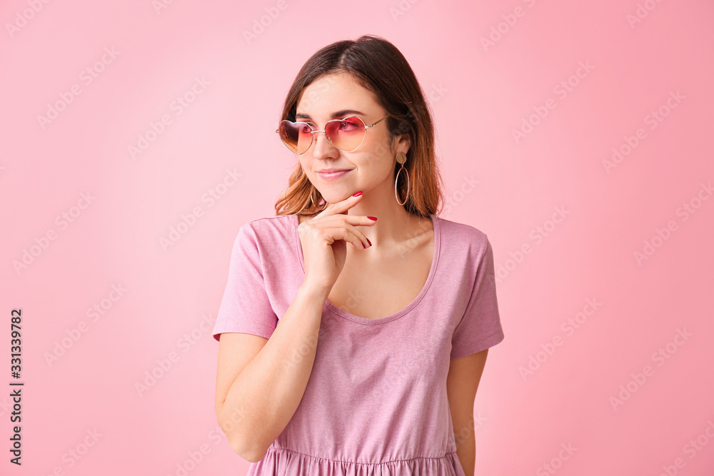 Young woman with stylish sunglasses on color background