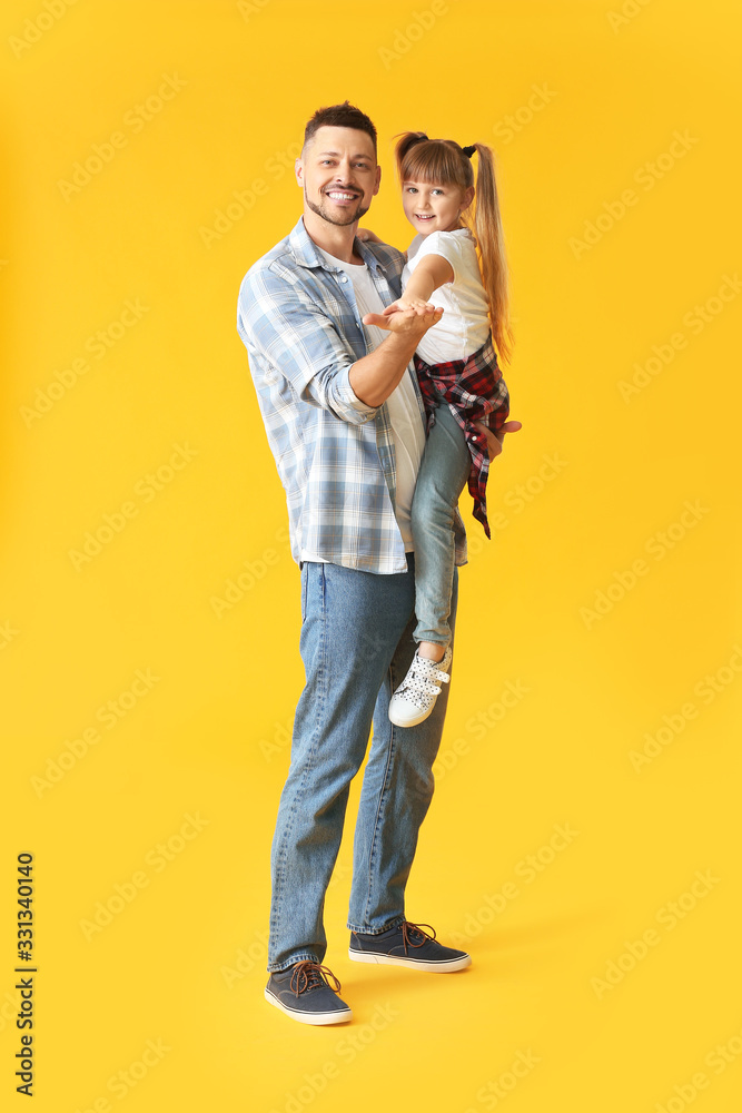 Father and his little daughter dancing against color background