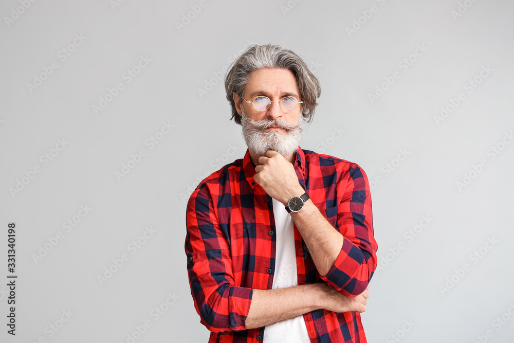 Stylish elderly man on grey background