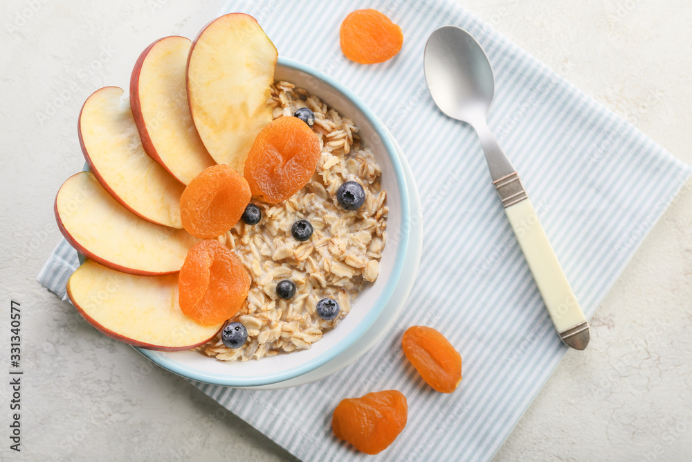 Bowl with tasty sweet oatmeal on white background