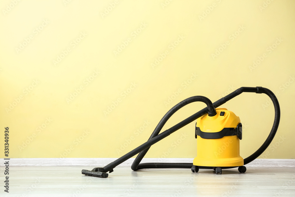 Modern vacuum cleaner near color wall