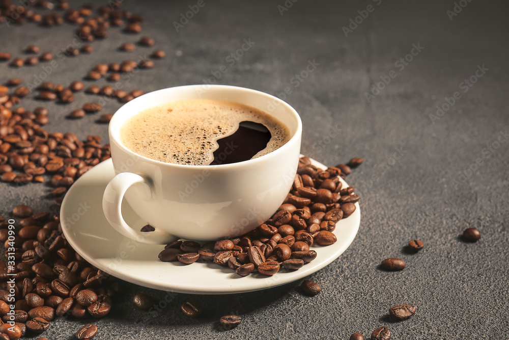 Cup of hot coffee and beans on table