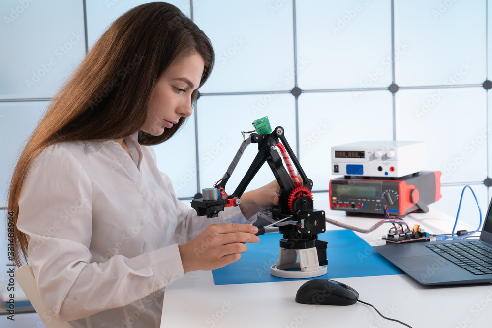 Woman student with industrial robot arm in laboratory