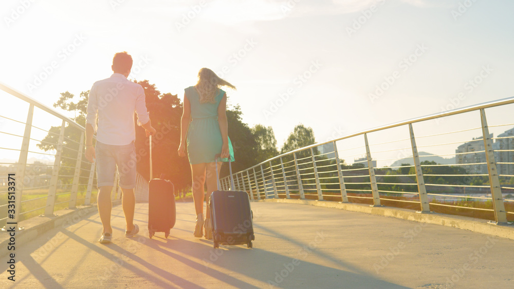 COPY SPACE: Young newlyweds carry their suitcases to the airport at sunset.