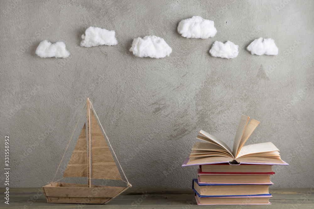 Education is a journey concept, toy boat and books like a sea waves on the wooden table, inspiration