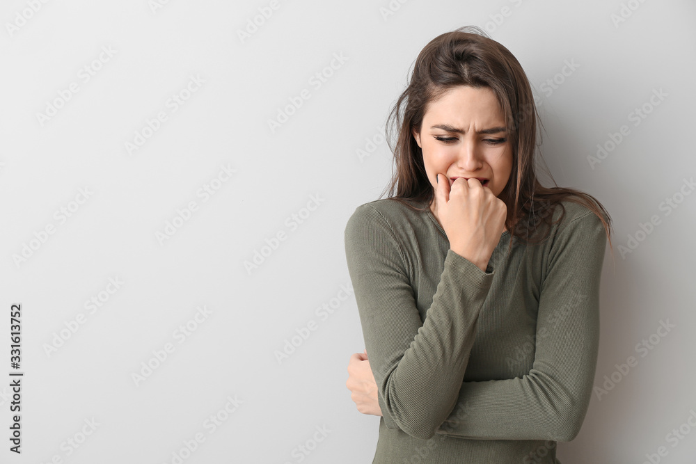 Depressed young woman on light background