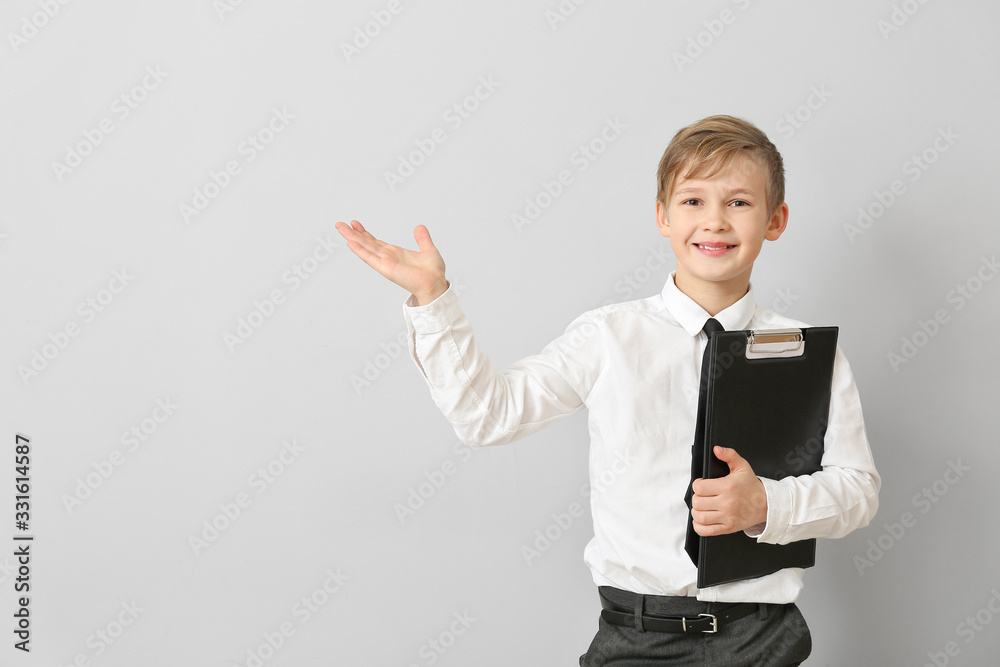 Portrait of little real estate agent showing something on light background