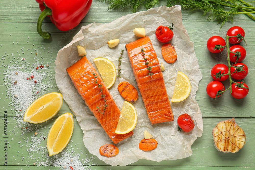 Paper with cooked salmon fillet and vegetables on table