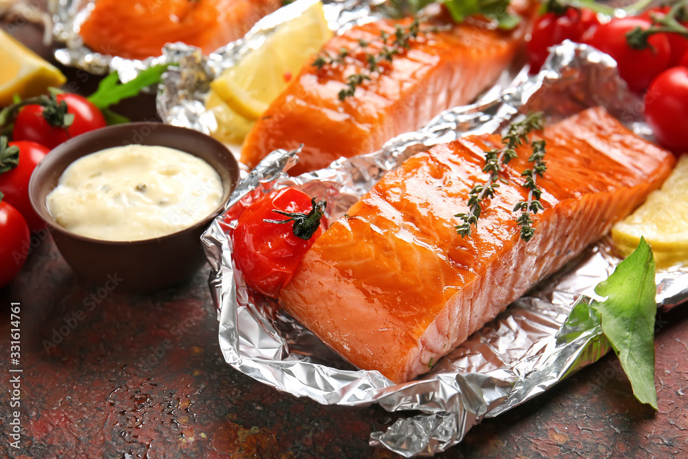 Foil with cooked salmon fillet and sauce on table