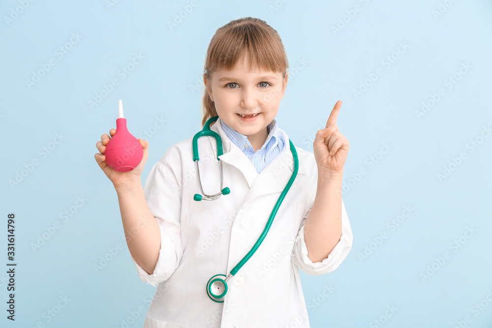 Cute little doctor with enema clyster on color background