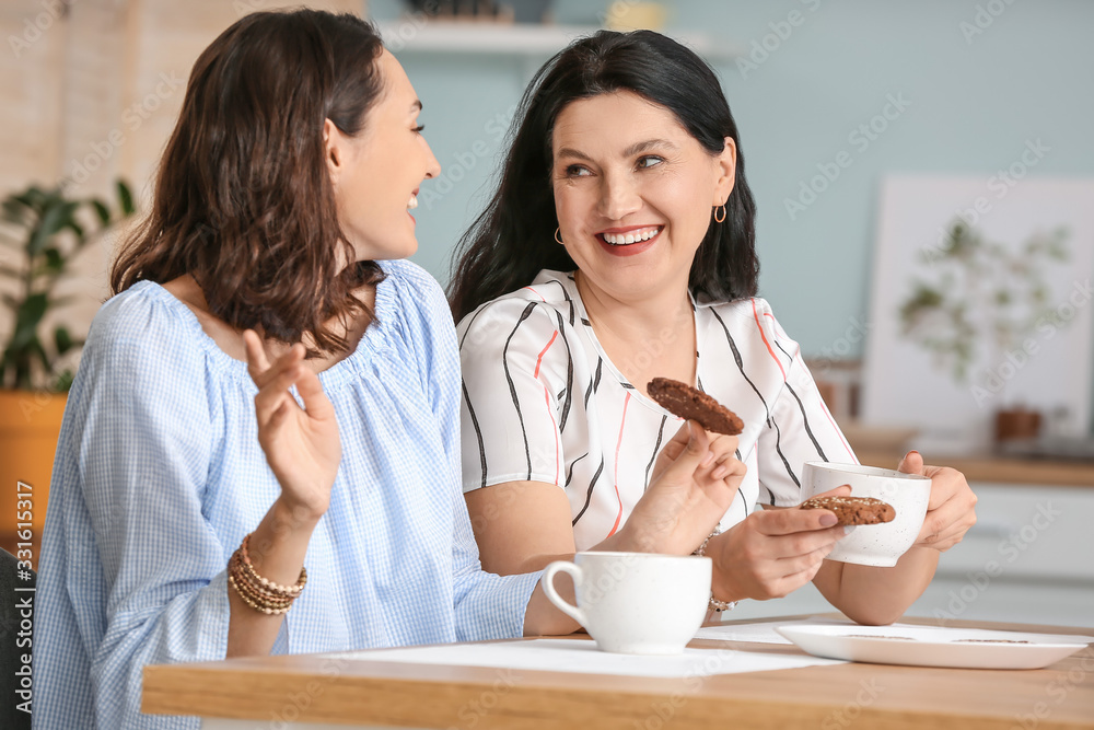 Adult daughter with her mother spending time together in kitchen