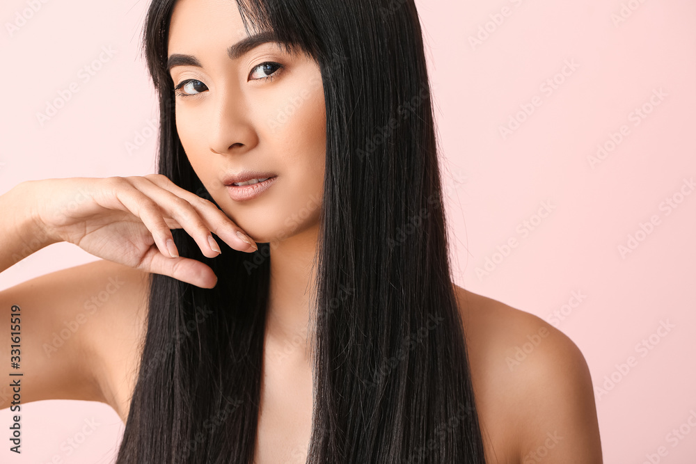 Young Asian woman with beautiful long hair on color background