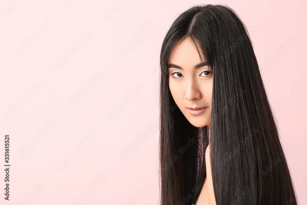 Young Asian woman with beautiful long hair on color background