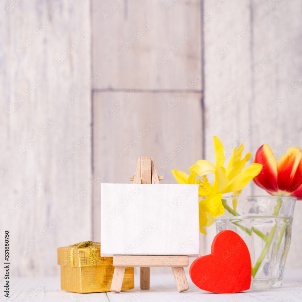 Tulip flower in glass vase with picture frame decor on wooden table background wall at home, close u