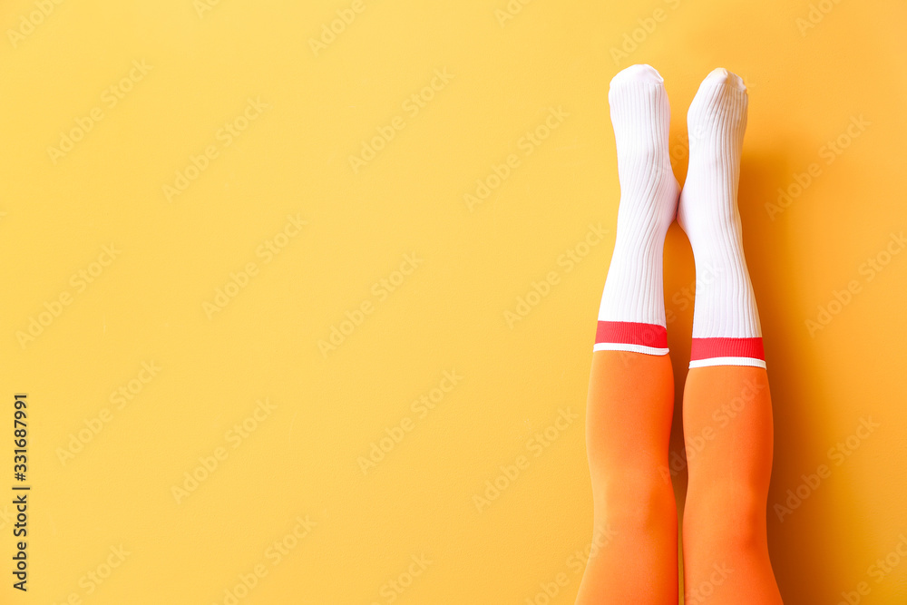 Legs of young woman in socks and tights on color background